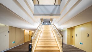 A modern hotel corridor with a central wooden staircase, glass railings, and wooden flooring. - Holiday Inn Shijiazhuang Central by IHG (Shijiazhuang)