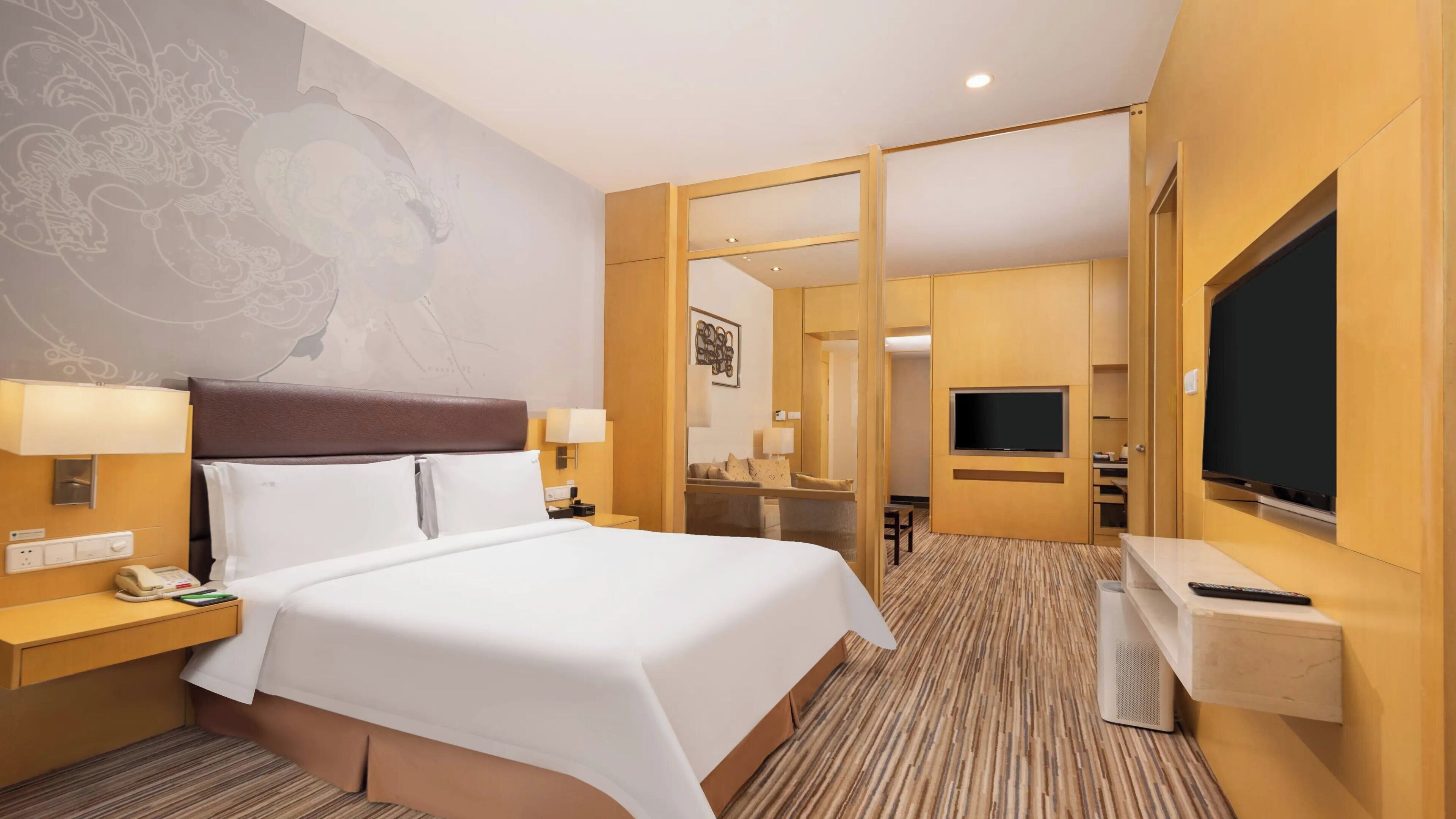 A hotel room with a large bed, bedside lamps, a TV, and a mirror.