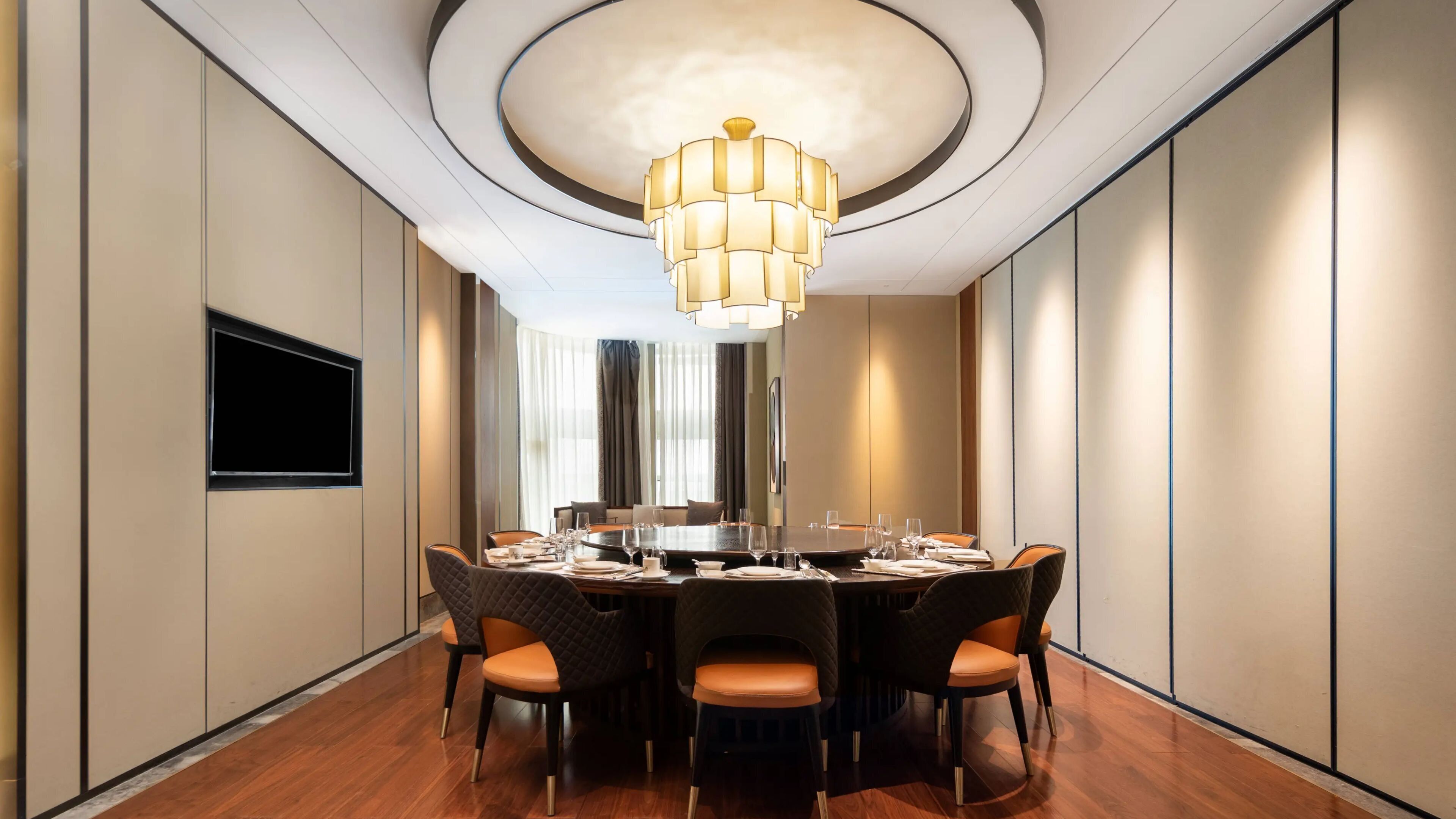 A modern dining room with a round table, six chairs, and a chandelier.