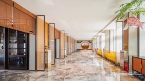 A hotel corridor with a polished marble floor, wooden paneling on the left, and glass partitions on the right. - Holiday Inn Shijiazhuang Central by IHG (Shijiazhuang)