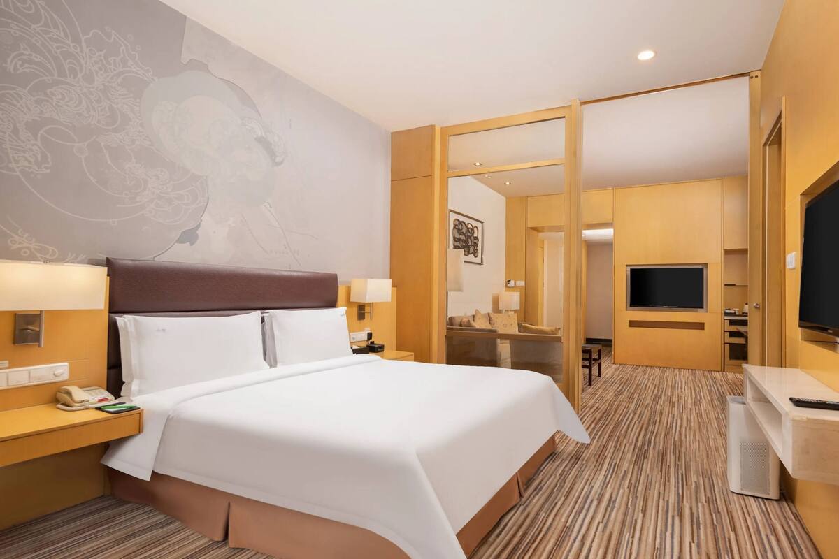 Ein Hotelzimmer mit einem großen Bett, Nachttischlampen, einem Fernseher und einem Spiegel.