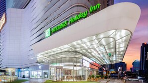 Et Holiday Inn hotel med moderne arkitektur, karakteriseret ved en buet glasfacade og et rummeligt indgangsparti.