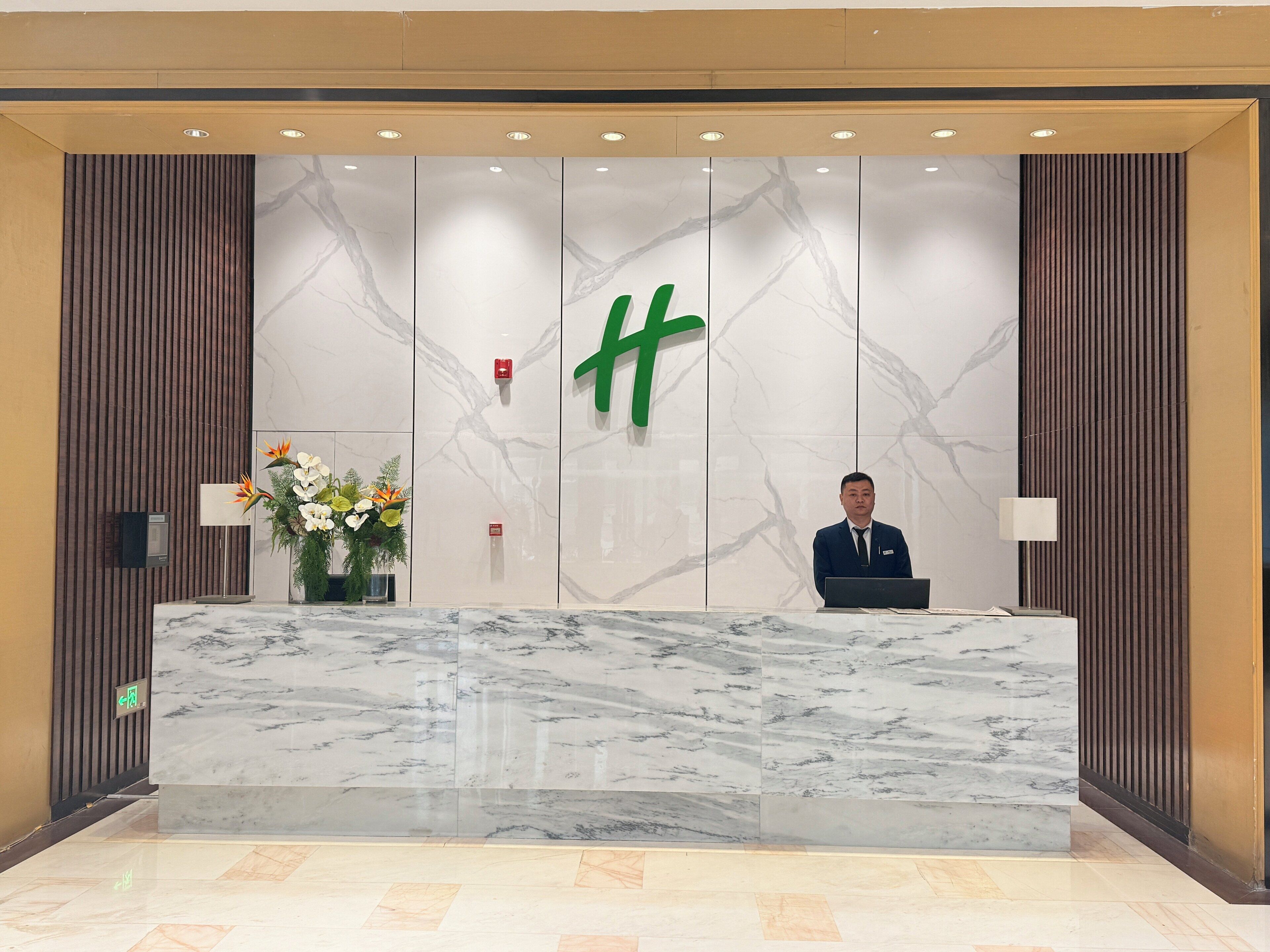 A reception desk with a marble top, a large green logo, and a modern design.