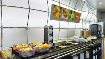 Zona de buffet con diversas opciones de comida, incluyendo pan, pastelería y una estación de café.