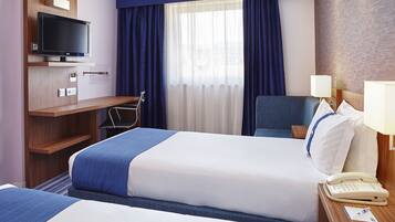 A hotel room with two beds, a TV, a desk, and a phone on the nightstand.