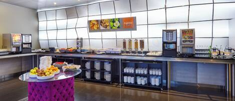 A modern breakfast buffet with a variety of food options and self-service beverage dispensers.