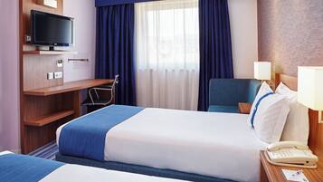 Habitació d'hotel amb llit, escriptori, cadira, televisió i telèfon.