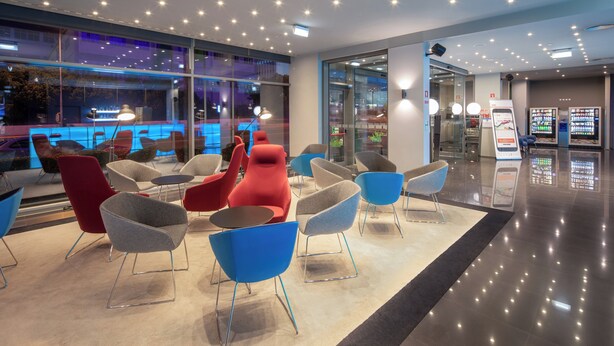 Een moderne lobby met eigentijdse stoelen, een glazen wand en een automaat.