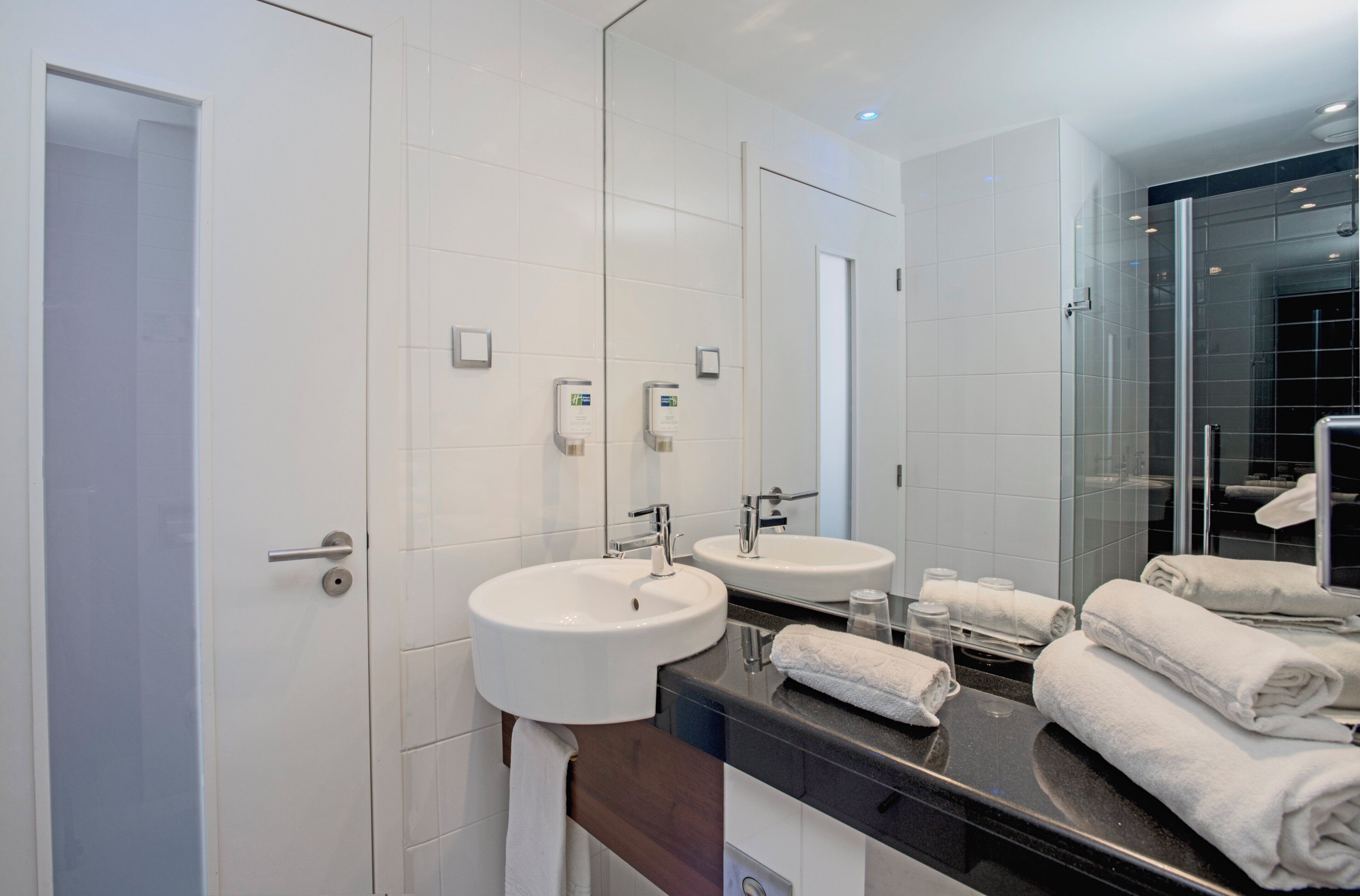 A modern bathroom with two sinks, a large mirror, and a glass shower enclosure.