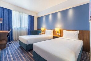 A hotel room with two beds, a desk, a chair, and a window with curtains. - Holiday Inn Express Lisbon - Alfragide by IHG (Oeiras)