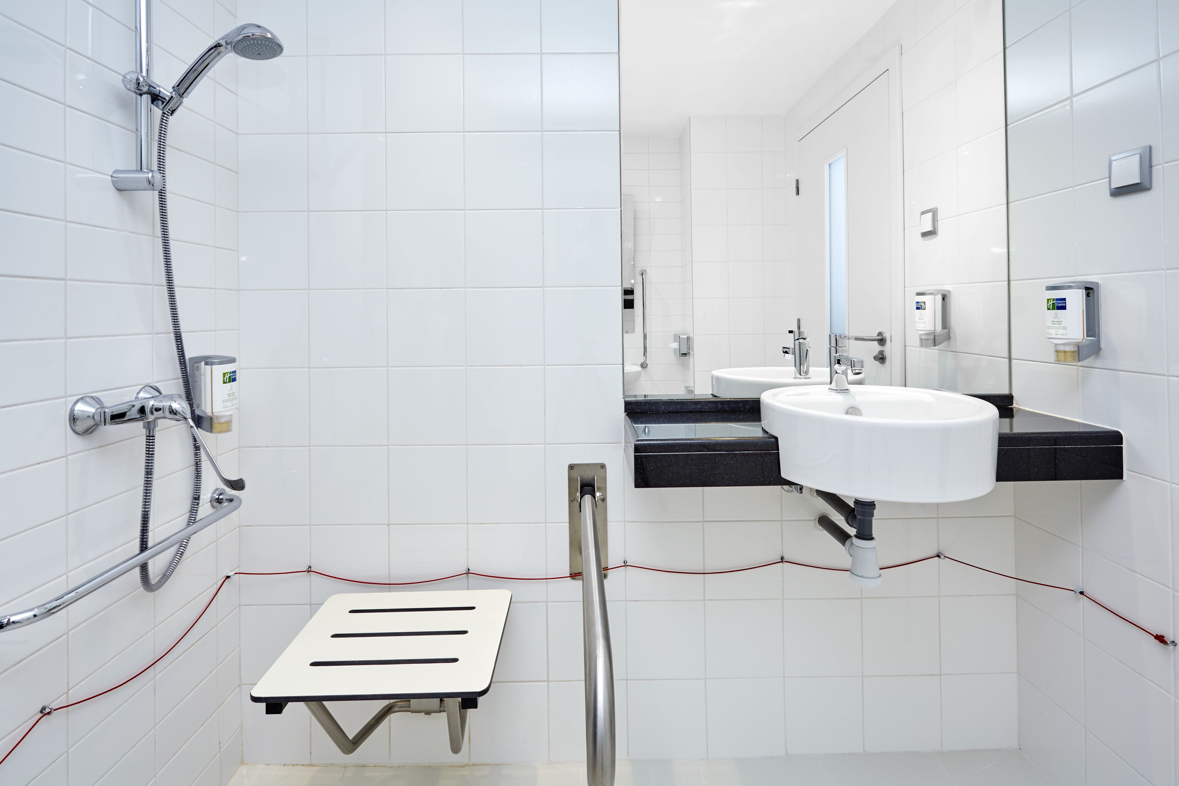 Een moderne badkamer met een douche, een wastafel en een spiegel.