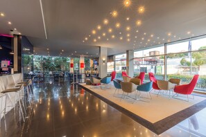 A modern interior with a seating area, large windows, and a view of the outside. - Holiday Inn Express Lisbon - Alfragide by IHG (Oeiras)