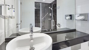 Een moderne badkamer met een groot wit wastafelmeubel, een douche met glazen wanden en een spiegel met chromen lijst.