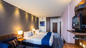 Een hotelkamer met twee bedden, een bureau, een televisie en een zithoek.