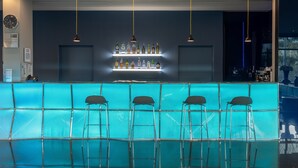 A bar area with a blue counter, multiple hanging lights, and bar stools. - Holiday Inn Express Lisbon - Alfragide by IHG (Oeiras)