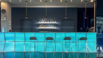 Zona de bar con mostrador azul, varias luces colgantes y taburetes.