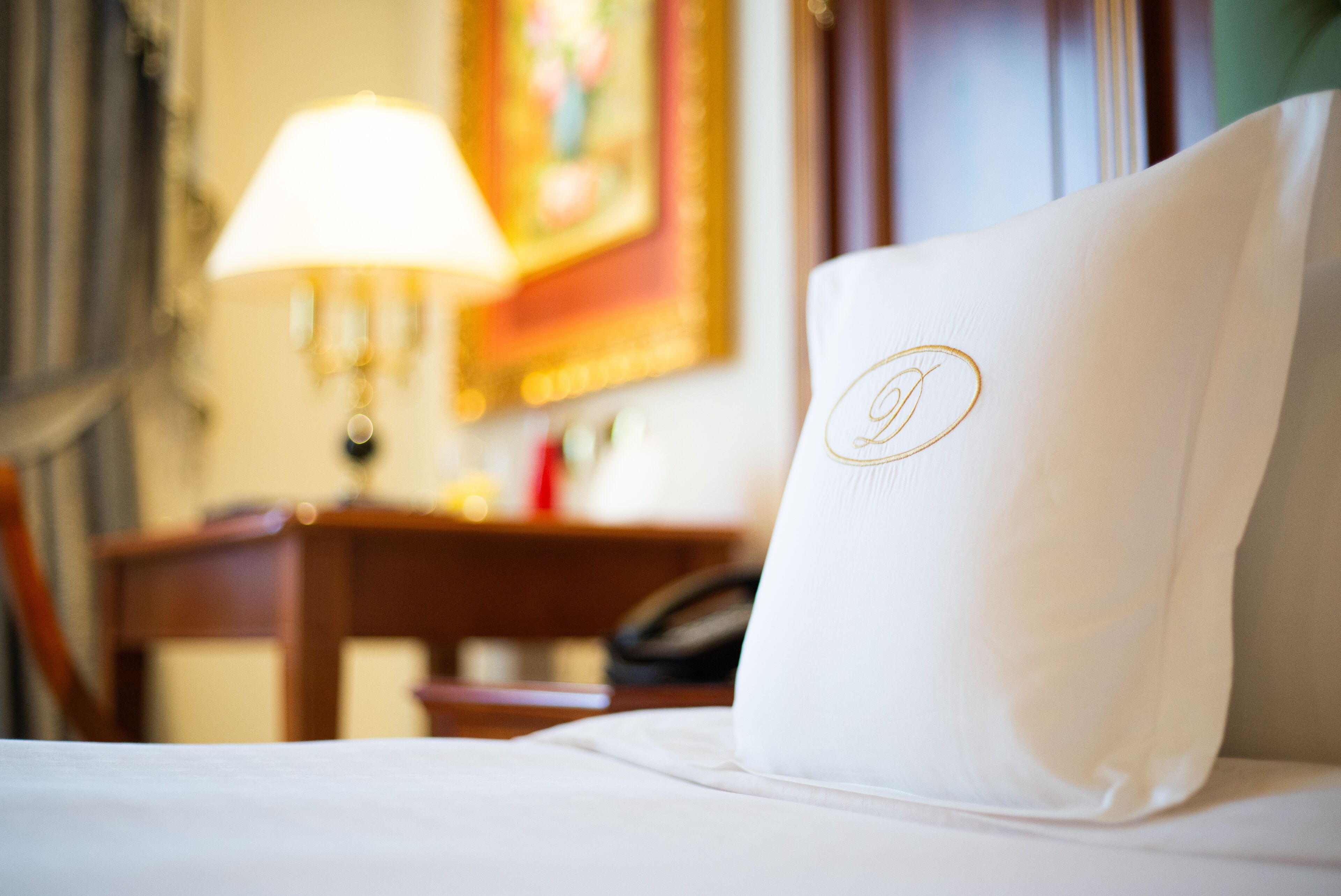 Ein Hotelzimmer mit einem ordentlich bezogenen Bett, einer Lampe und einem Bild an der Wand.