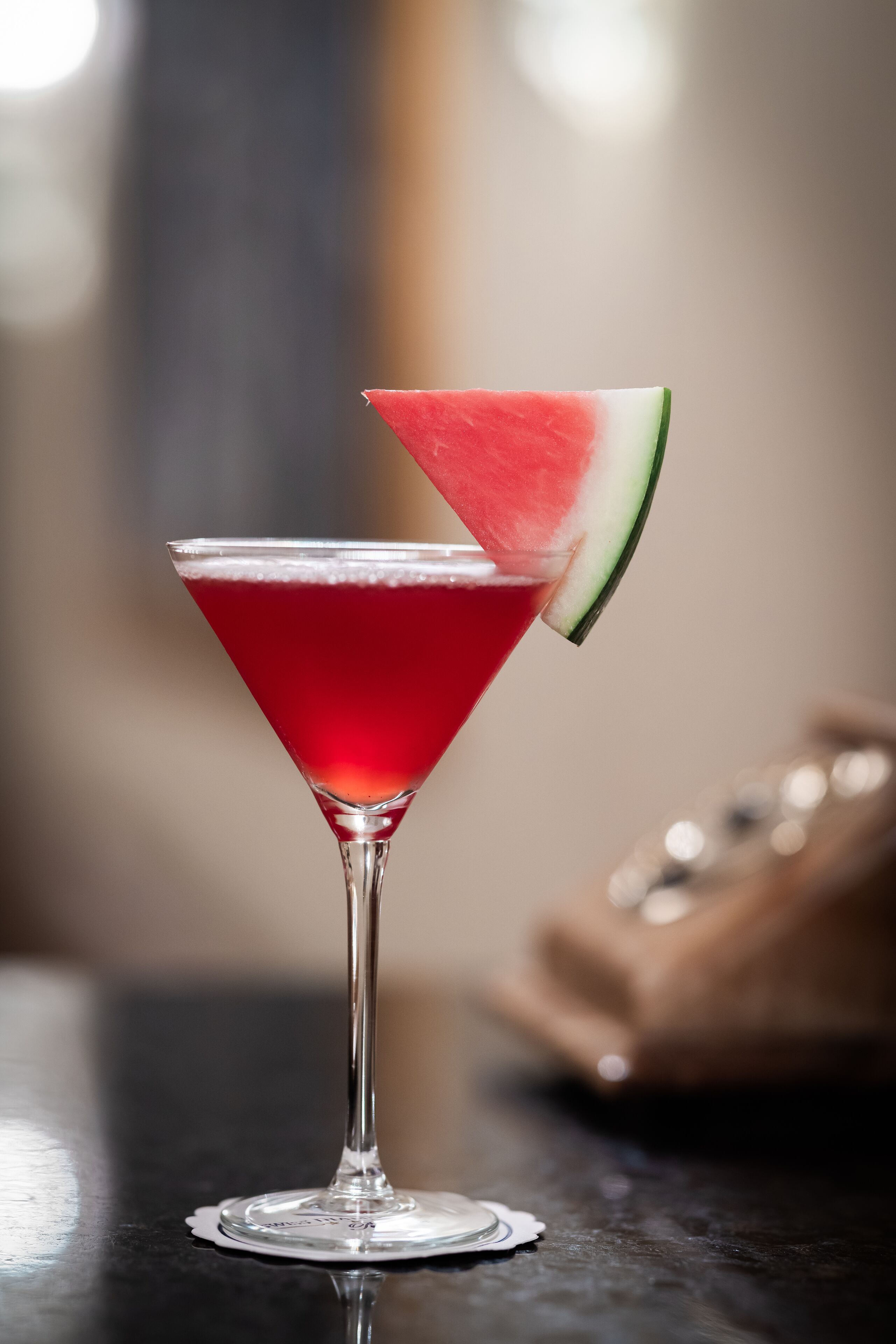 Ein Martini-Glas mit roter Flüssigkeit und einem Wassertangoschnitzchen am Rand.