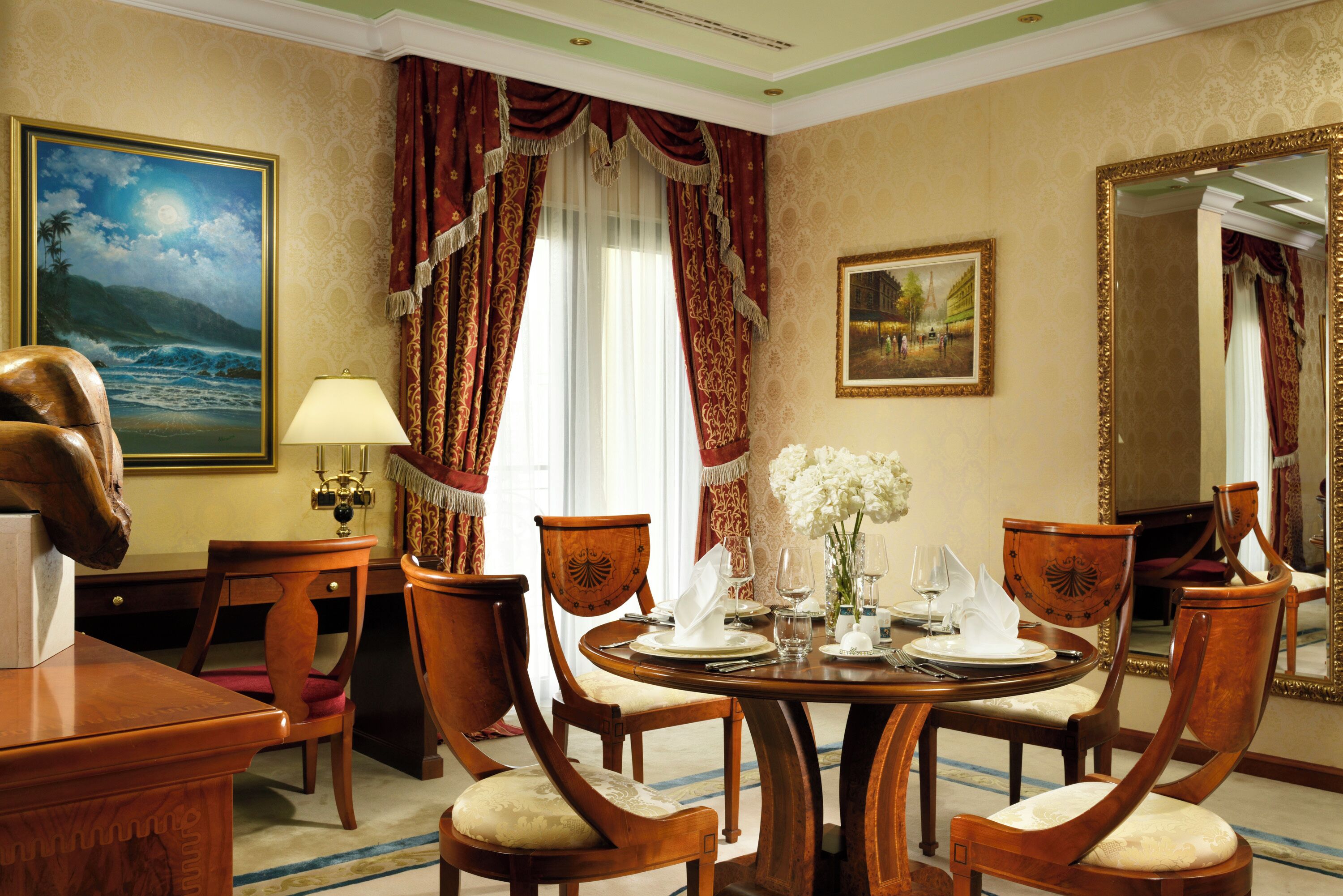 A dining room with a round table set for four, surrounded by wooden chairs with cushioned seats.