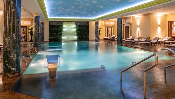 A luxurious indoor pool with marble columns, a glass ceiling, and lounge chairs. - Swiss Diamond Hotel Prishtina (Pristina)