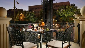 An outdoor dining area with a table set for two, surrounded by ornate metal chairs and a decorative metal fence. - Swiss Diamond Hotel Prishtina (Pristina)