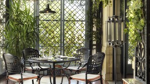 A dining area with a round table, four chairs, and hanging pendant lights. - Swiss Diamond Hotel Prishtina (Pristina)