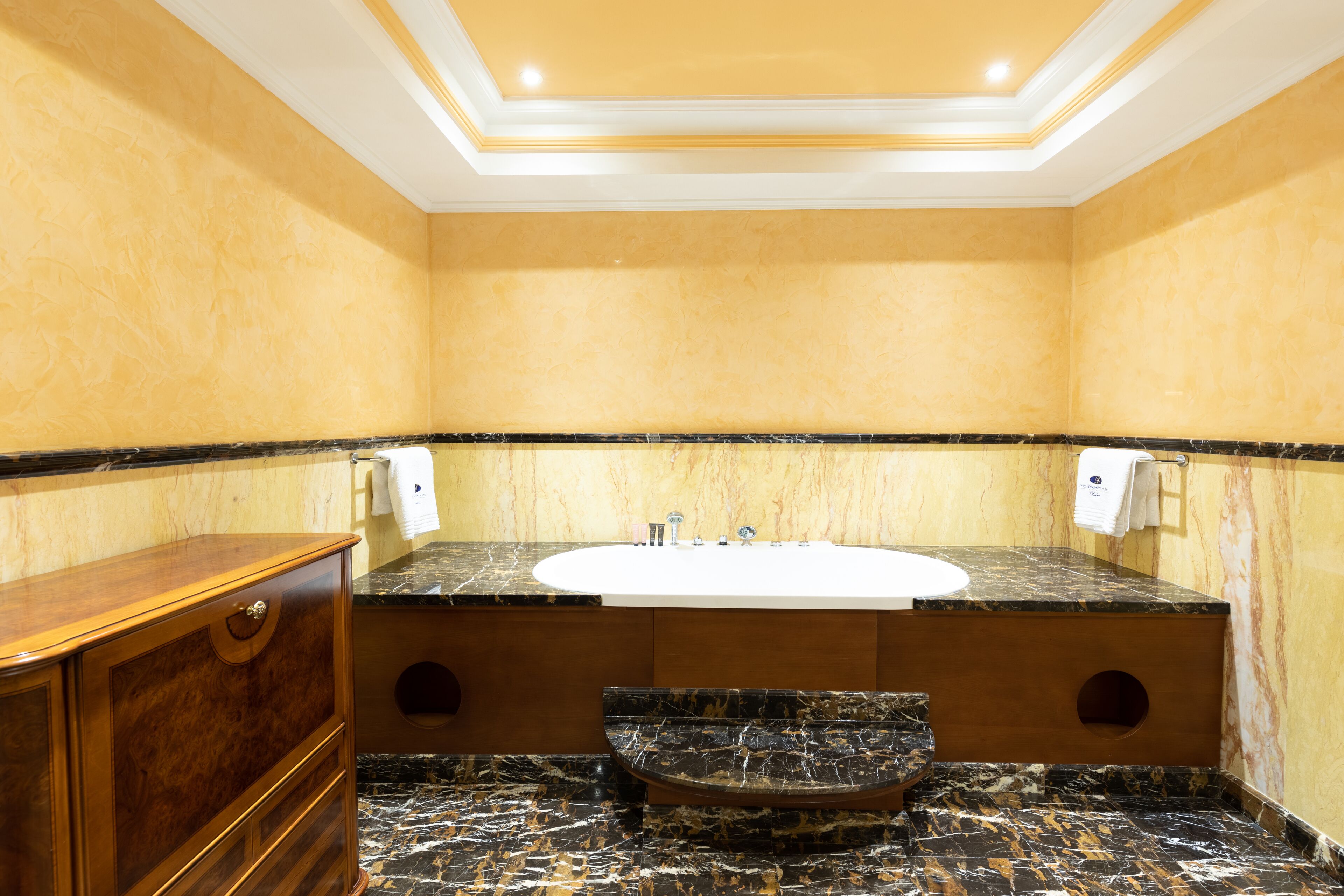 Un bagno con lavabo in marmo, mobile contenitore in legno e pavimento in marmo.