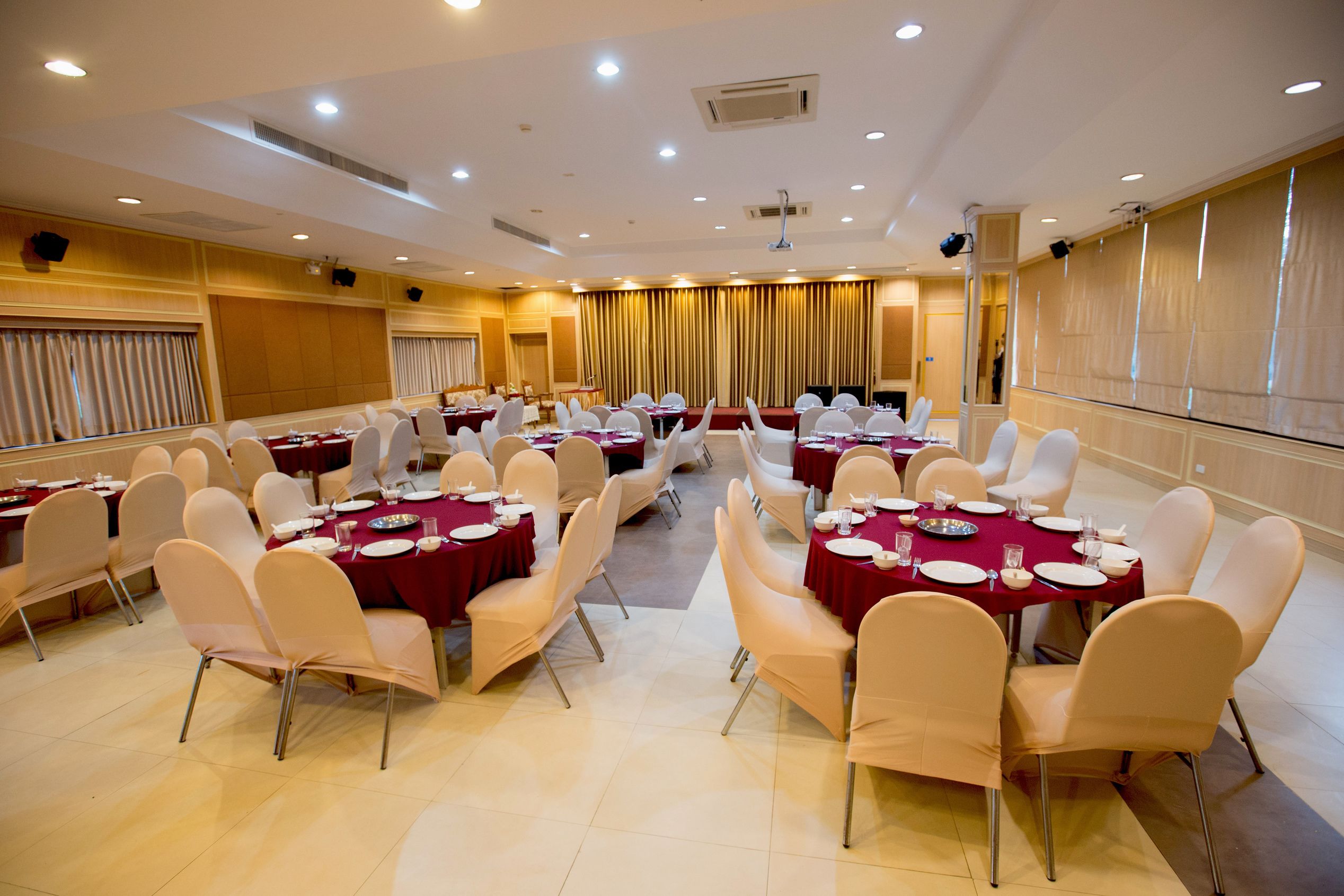 A conference room with multiple tables set for dining, equipped with chairs and tables.