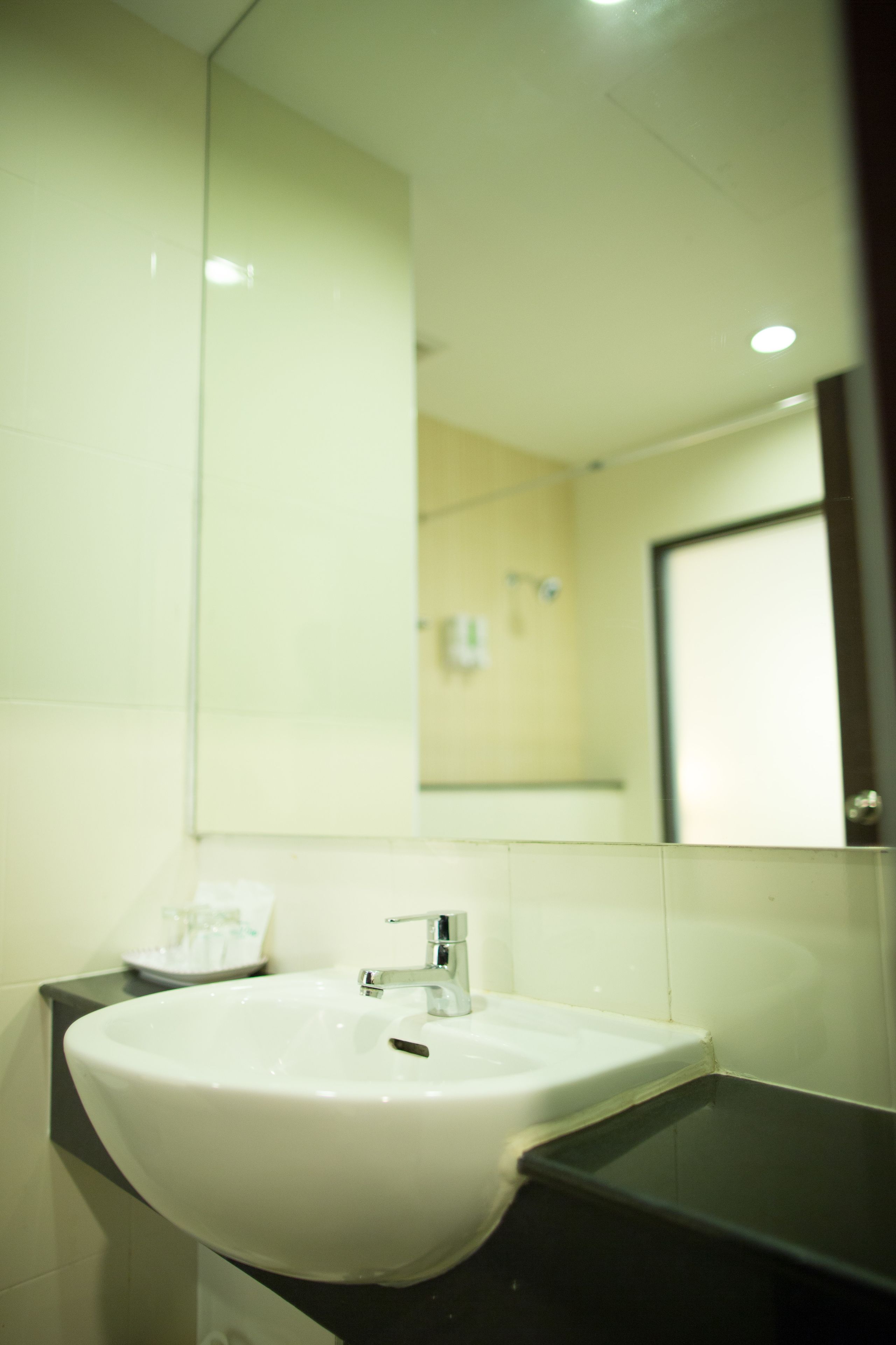 A bathroom with a white sink, a mirror, and a black countertop.