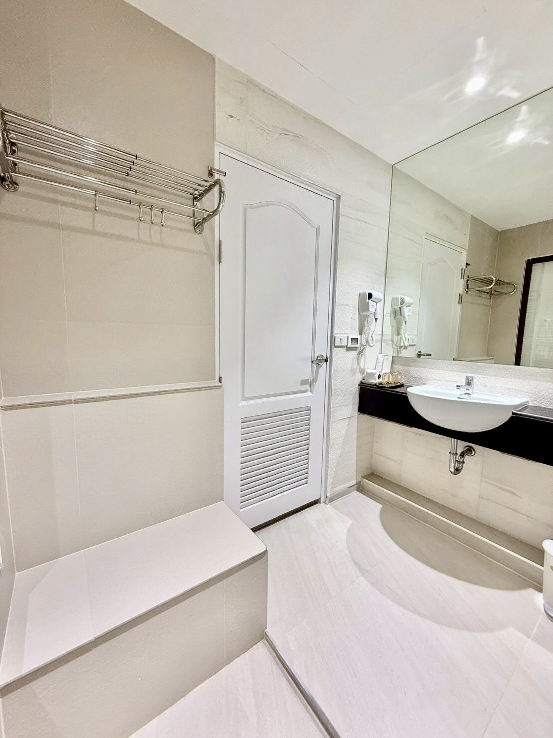 Un baño moderno con un tocador blanco, un espejo grande y un perchero para toallas.