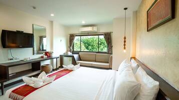A hotel room with a large bed, a TV, a desk, and a window with curtains.