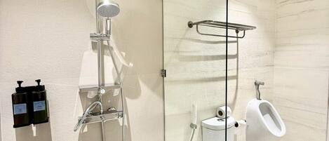 A modern bathroom with a glass-enclosed shower, a toilet, and a bidet.