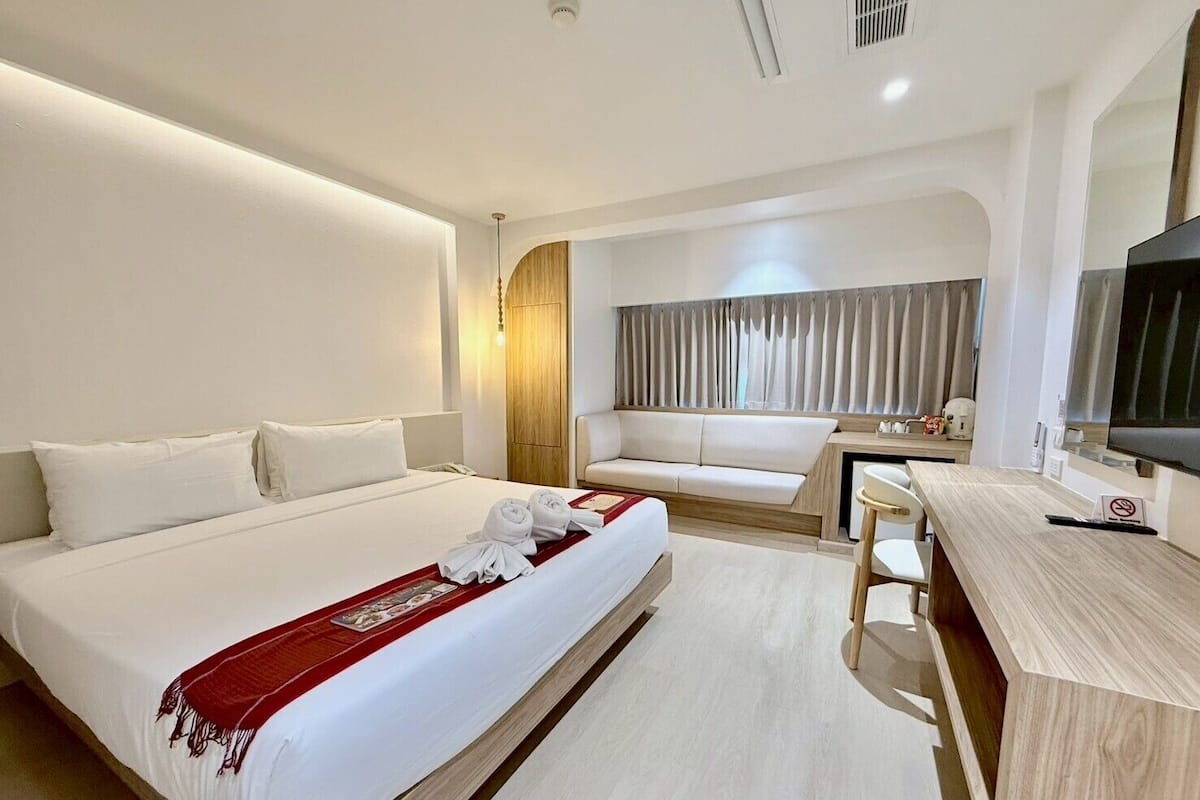 Une chambre d’hôtel équipée d’un lit, d’un bureau, d’une chaise, d’une télévision et d’une fenêtre avec des rideaux.