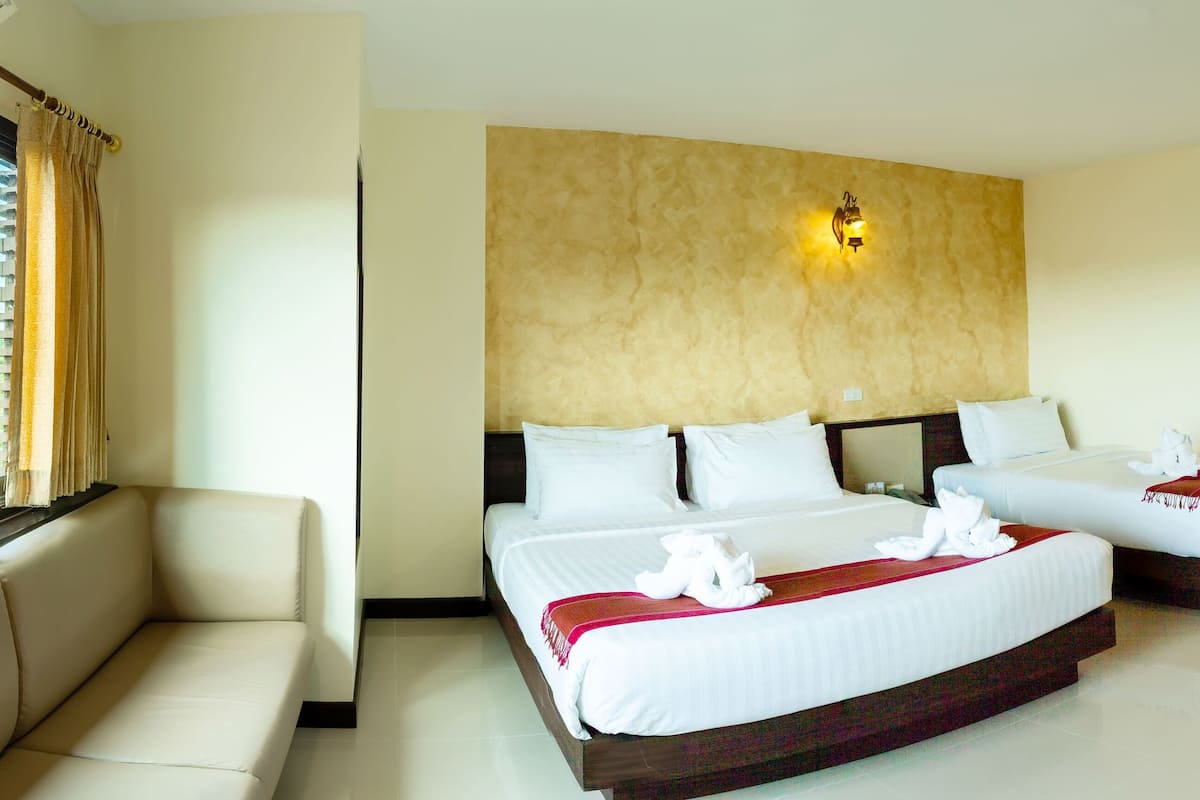 Une chambre d’hôtel avec une grande fenêtre, un canapé, deux lits et un luminaire fixé au mur.