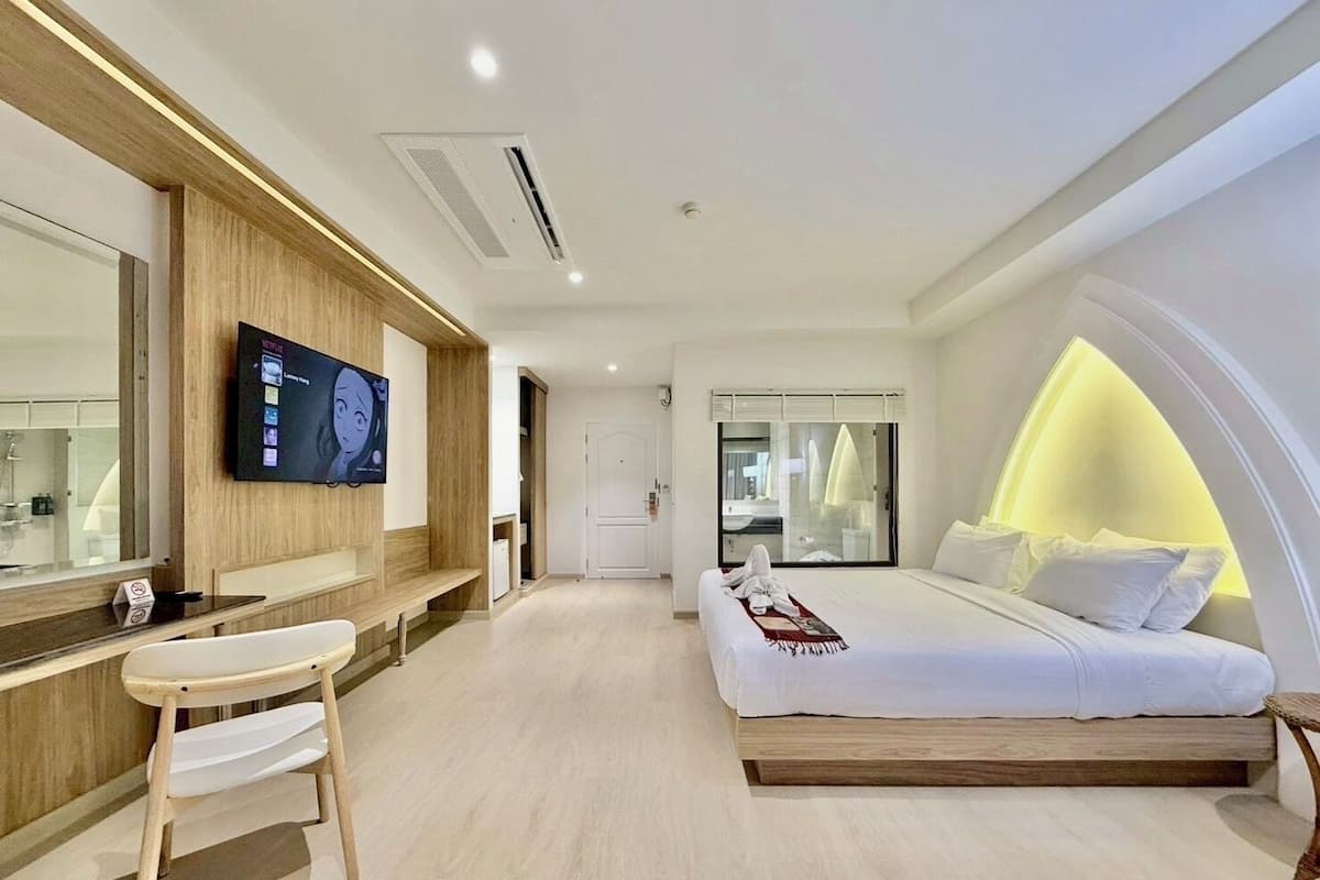 Une chambre d’hôtel moderne équipée d’un lit, d’une télévision, d’un bureau et d’une salle de bain.