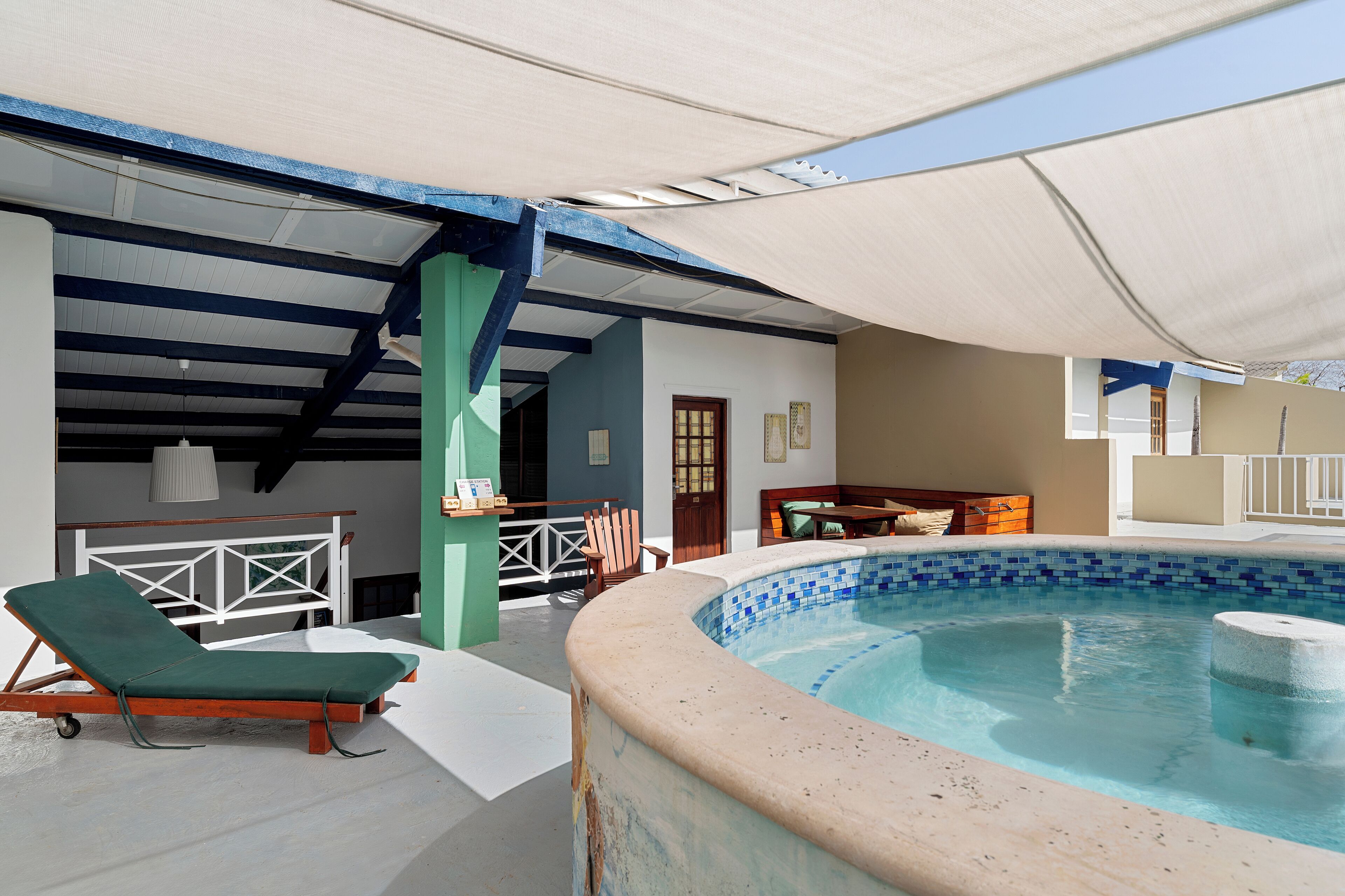 Una piscina techada al aire libre con una silla de descanso, un banco de madera y una mesa.
