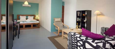 A modern hotel room with a bed, a desk, a chair, and a sofa.