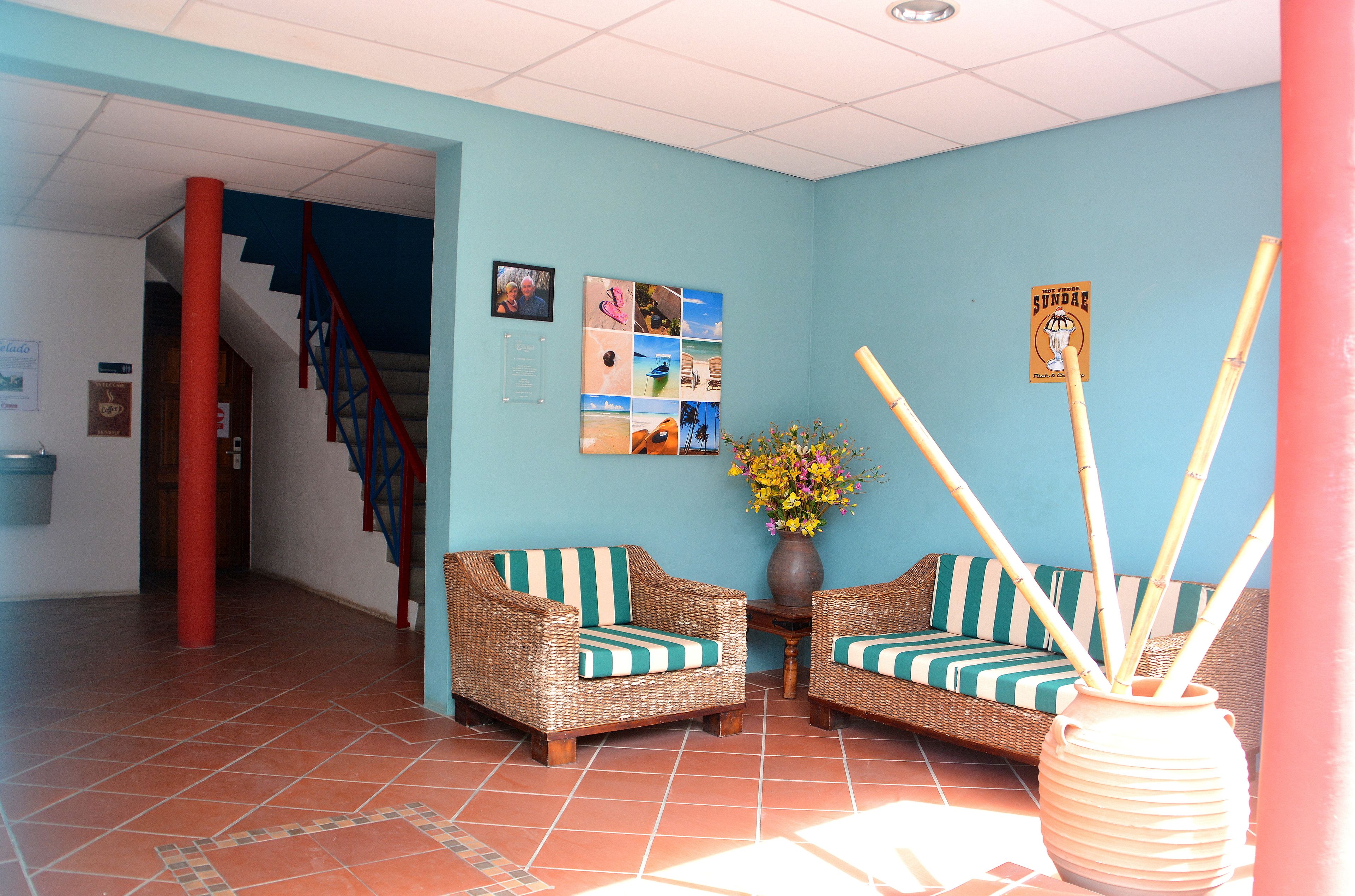 A reception area with wicker furniture, a vase with flowers, and a wall with photos and a sign.
