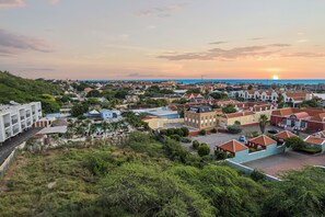 A coastal town with colorful buildings, a prominent church, and a view of the sunset over the ocean.