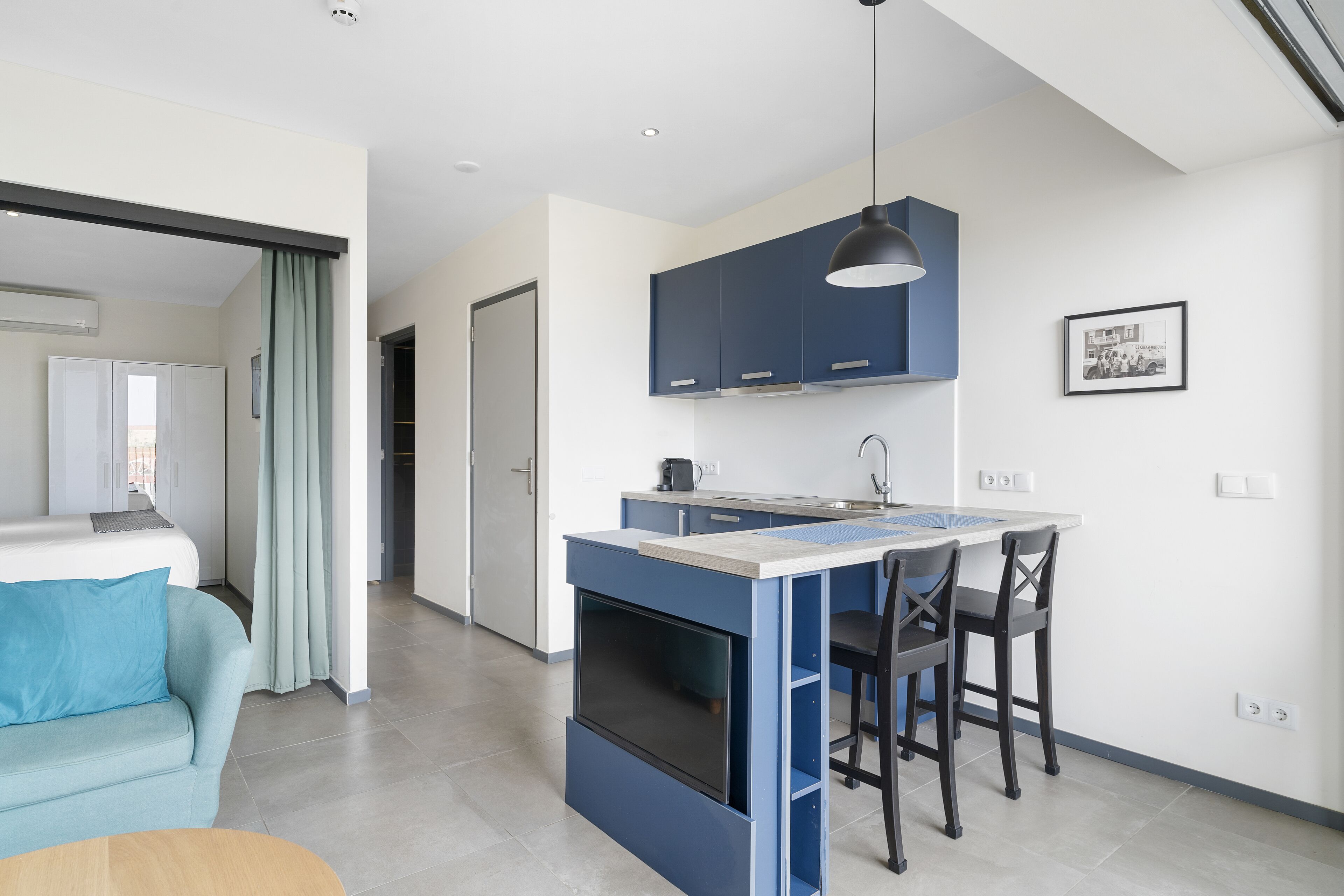 Una cucina moderna con mobili blu, un'isola centrale e un'area pranzo con due sedie.