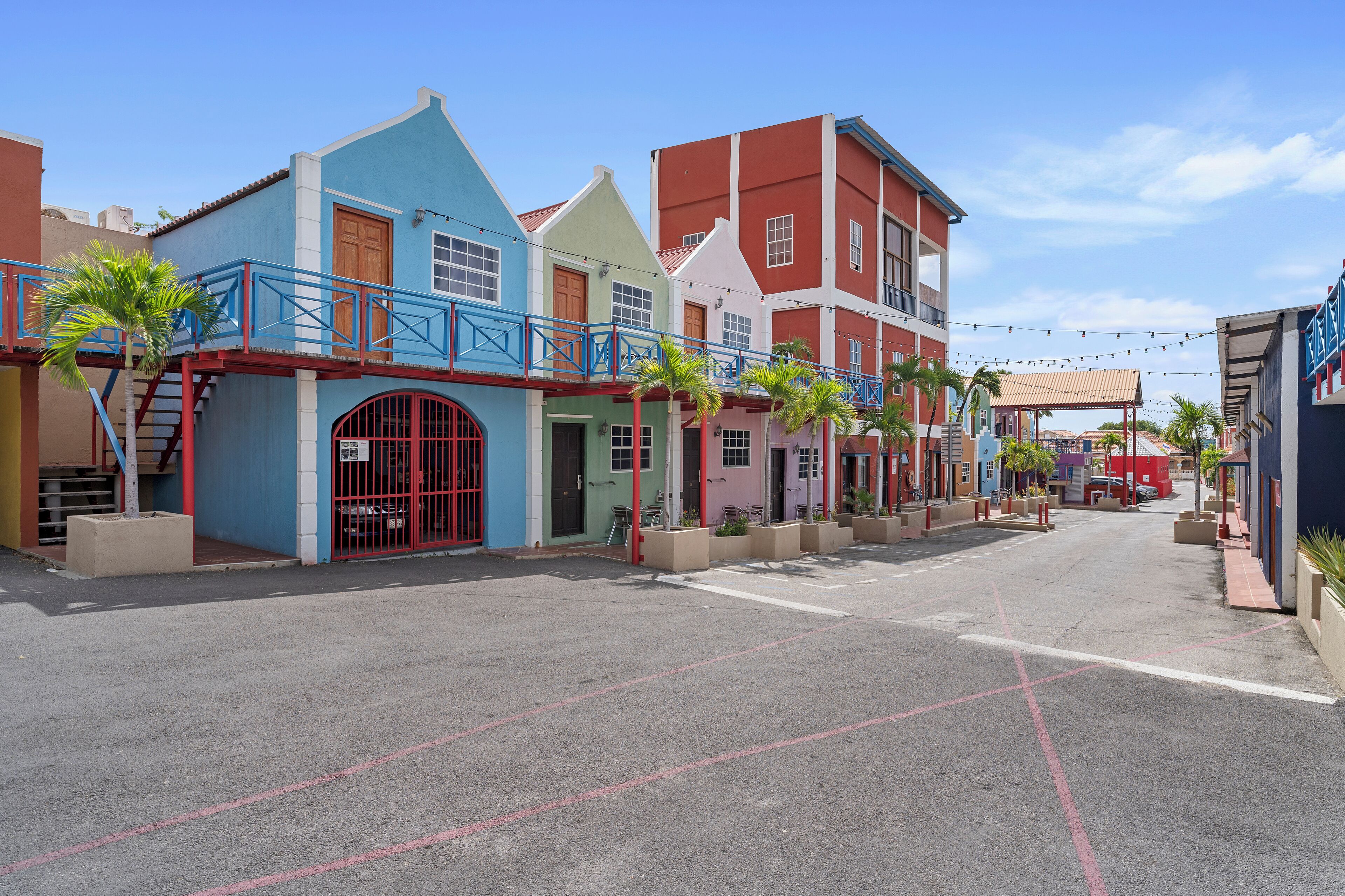 Un carrer amb edificis de colors, cel clar i una zona per a vianants.