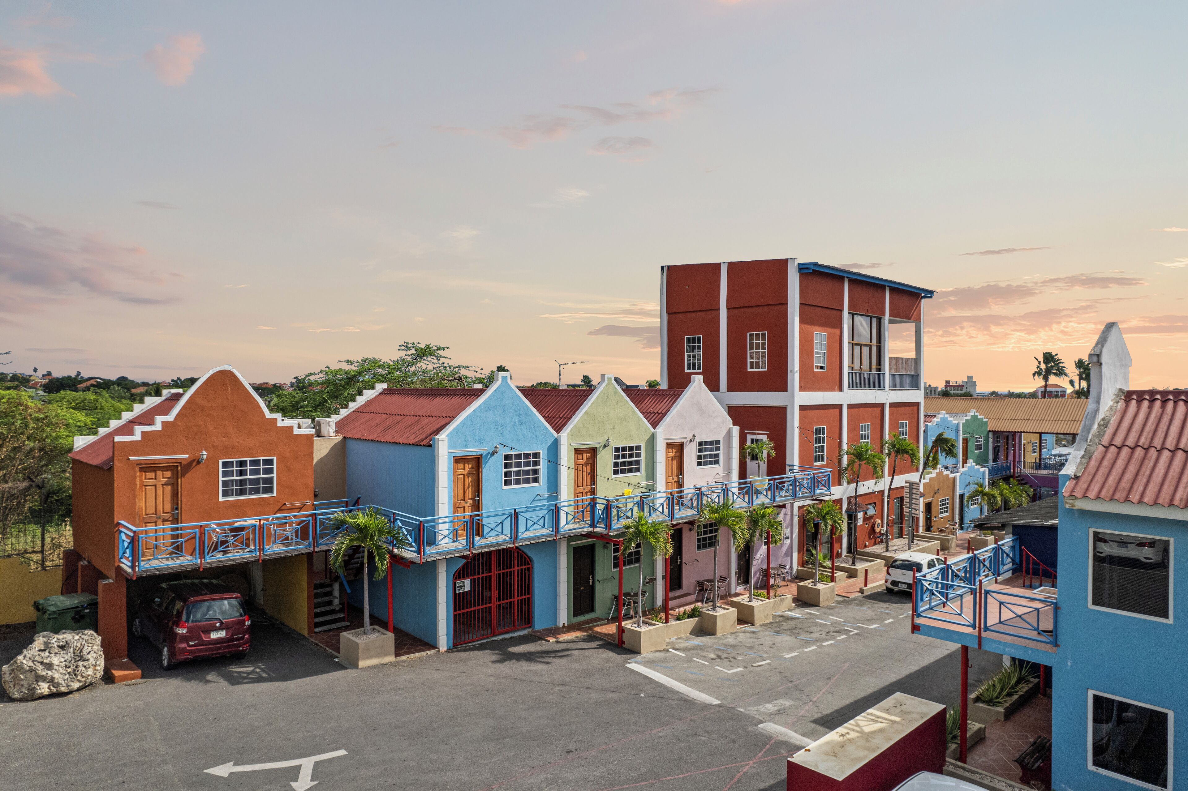 A row of colorful buildings with balconies and a red building with a garage.