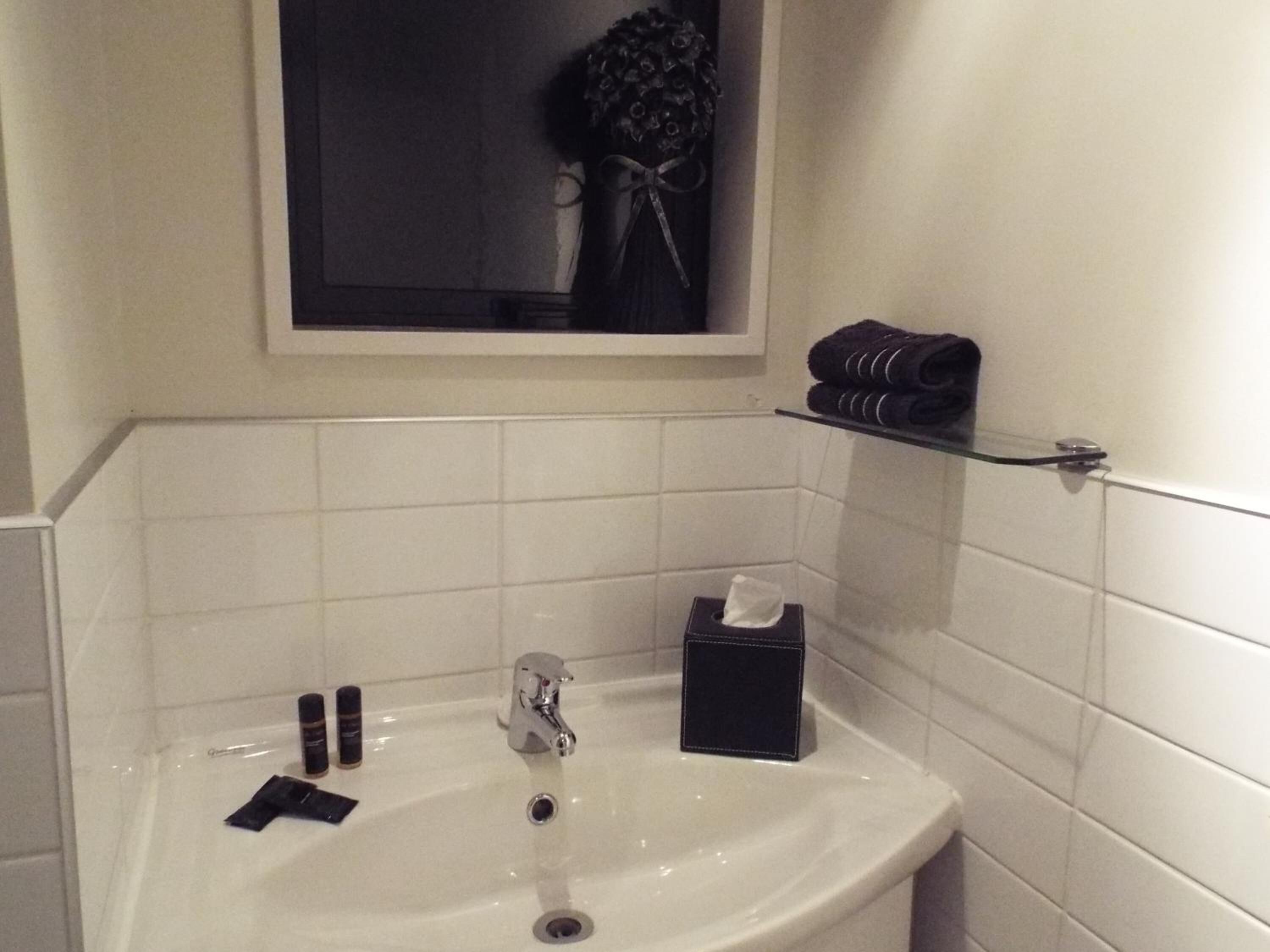 A bathroom with a white sink, a mirror, and a towel rack.