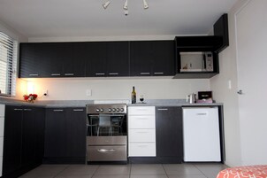 Una cocina compacta con armarios oscuros, horno empotrado, refrigerador y microondas.