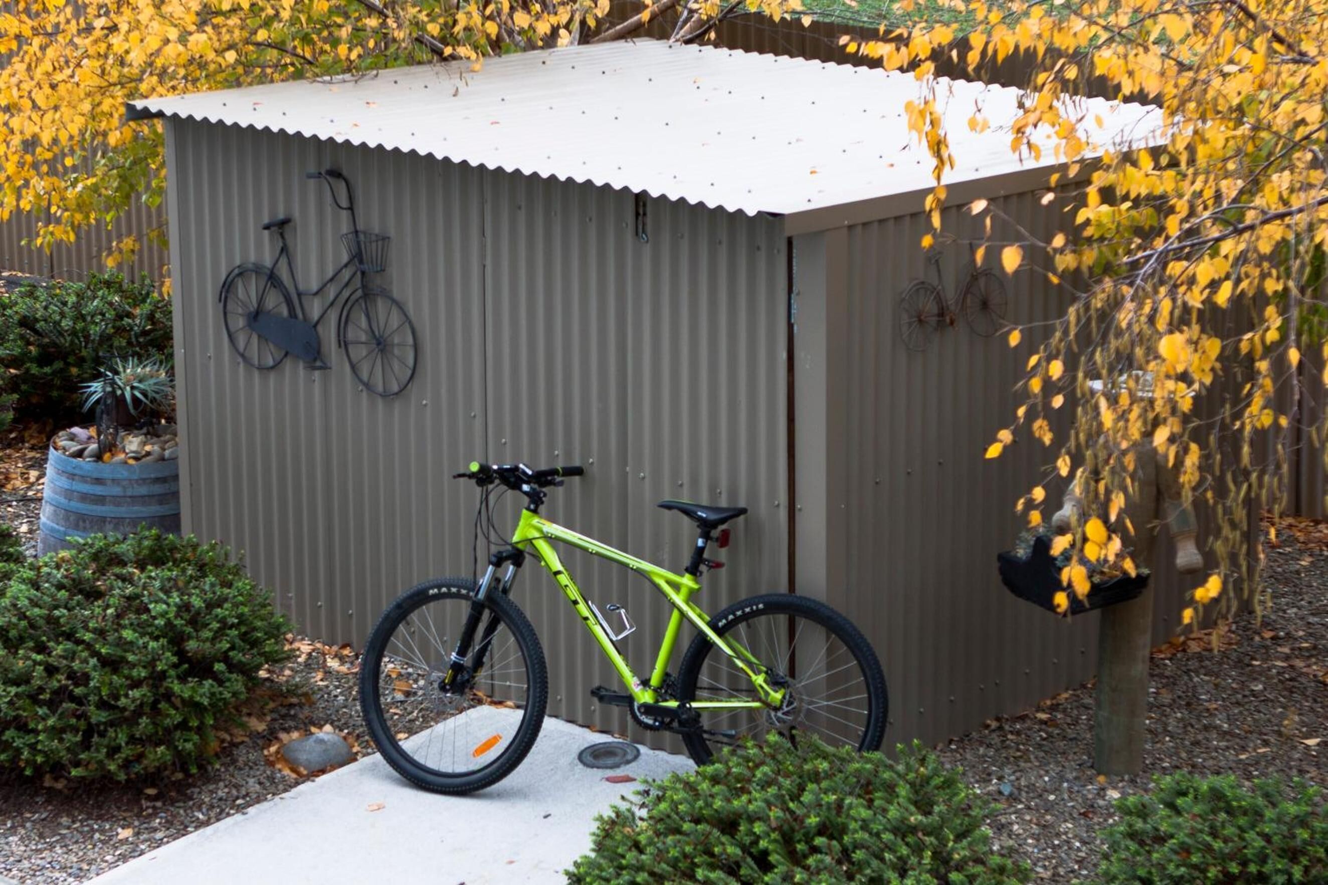 Un edificio pequeño de una sola planta con techo de lámina corrugada y una bicicleta colgada en la pared.