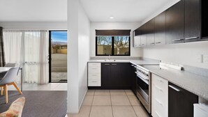Eine moderne Küche mit dunklen Schränken, einem eingebauten Backofen und einem großen Fenster.