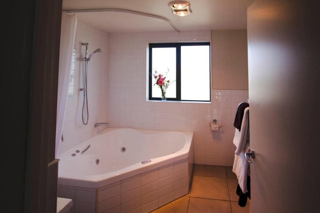 A modern bathroom with a freestanding bathtub, a shower, and a window with a view.