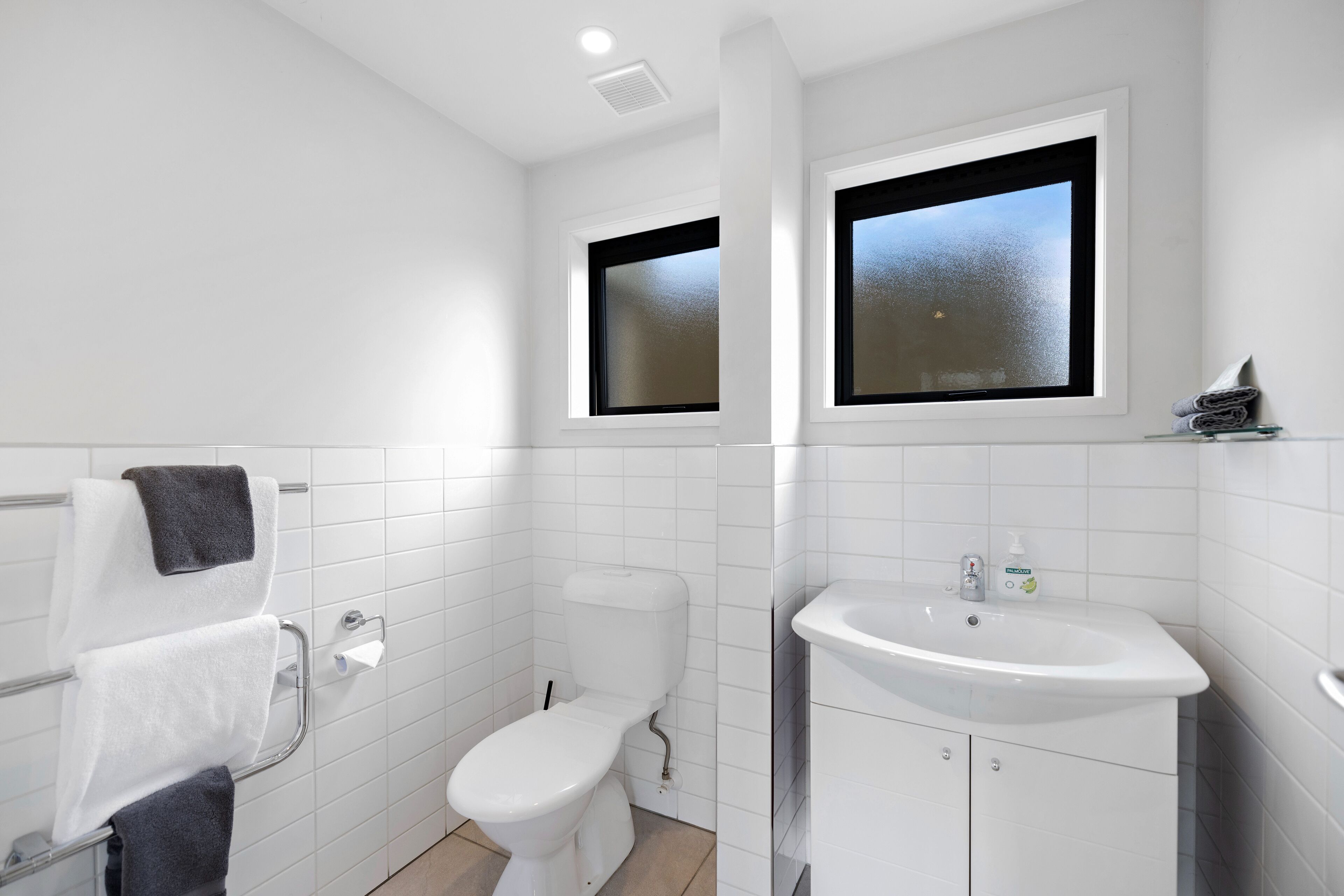 A modern bathroom with a toilet, sink, and towel rack.