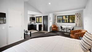 Ein modernes Hotelzimmer mit einem großen Bett, einer Küchenzeile, einem Essbereich und Blick auf die Stadt.