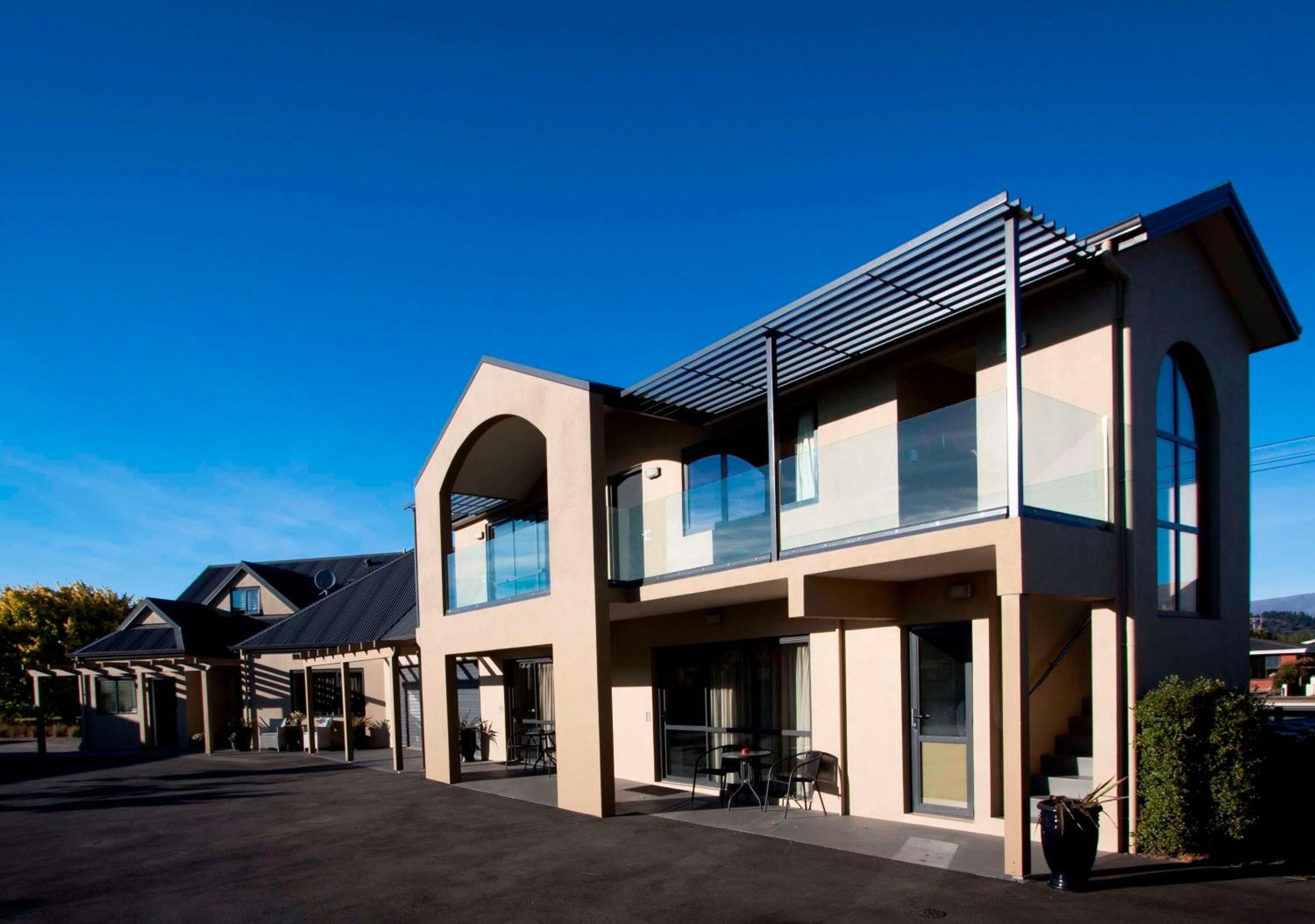 A modern two-story building with large windows, a covered patio, and a staircase leading to the upper level.